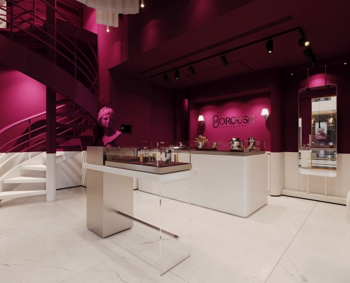 فضای داخلی گالری جواهر سروش با پالت بنفش و سفید و استیل و شیشه ، ویترین مرکزی و پله مارپیچ